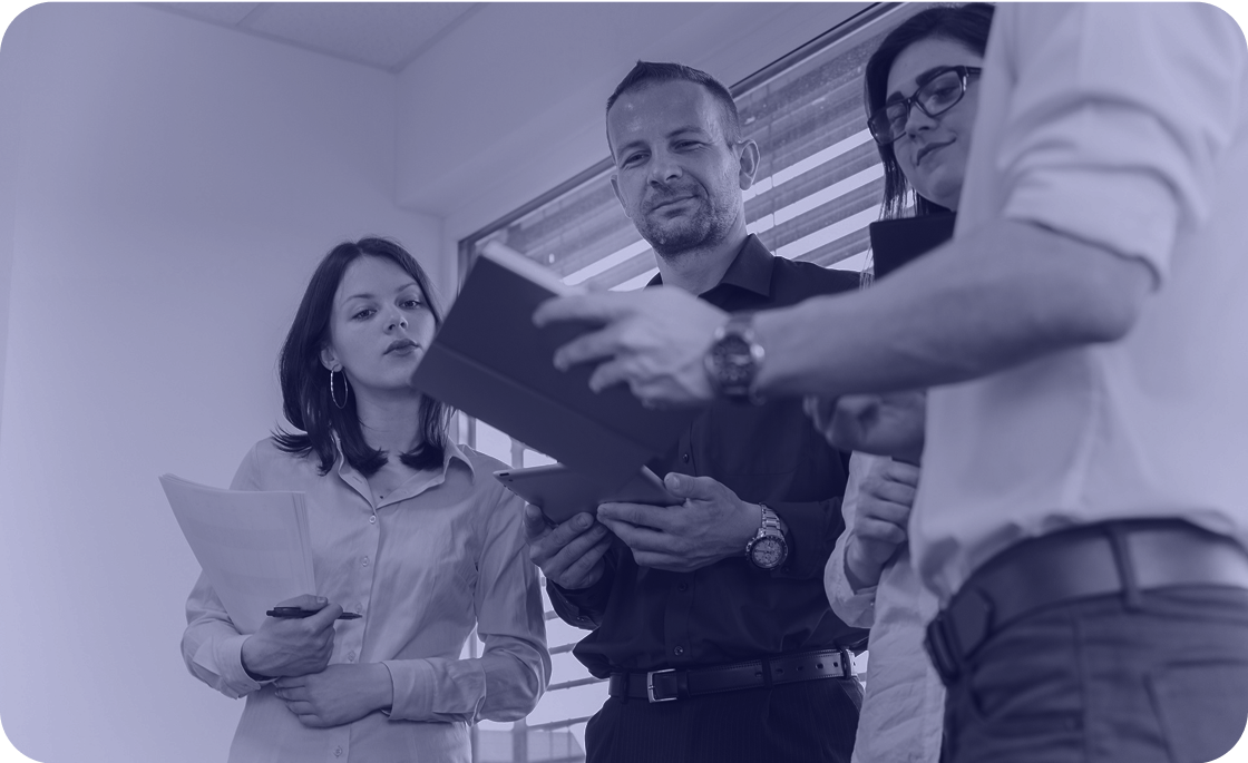 People working together, one of them holding a tablet, another holding a notebook